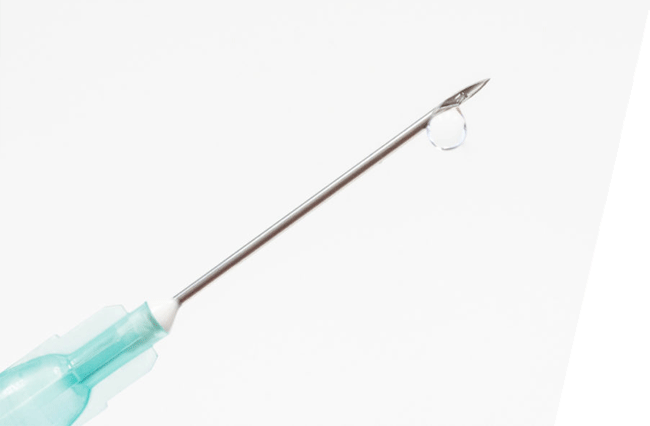 A drop of medicine forming at the tip of a syringe