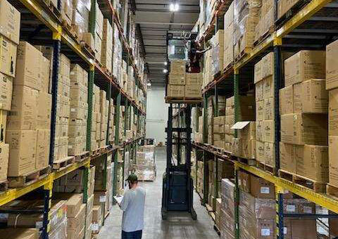 A forklift retrieving corrugated boxes from inside a warehouse