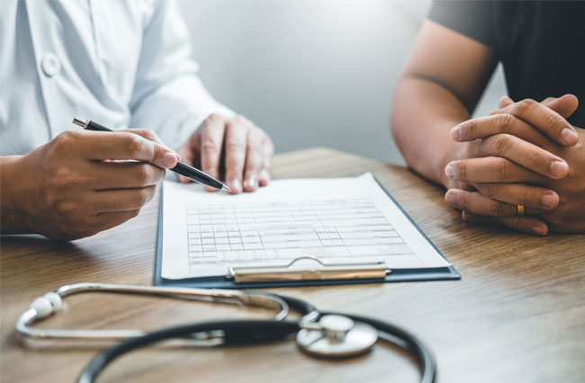 A Diabetes doctor and diabetic patient reviewing data on a chart while seated at a table