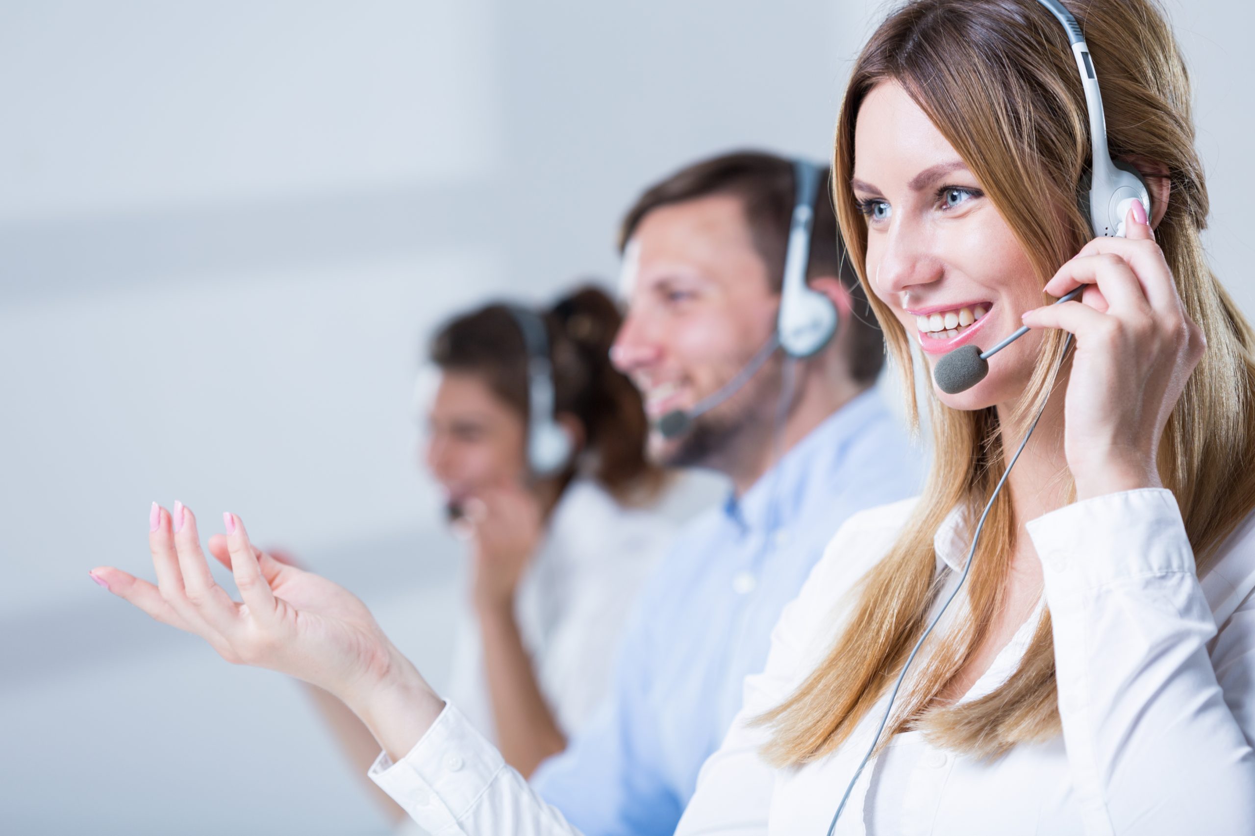 Three call center employees taking phone calls with headsets.